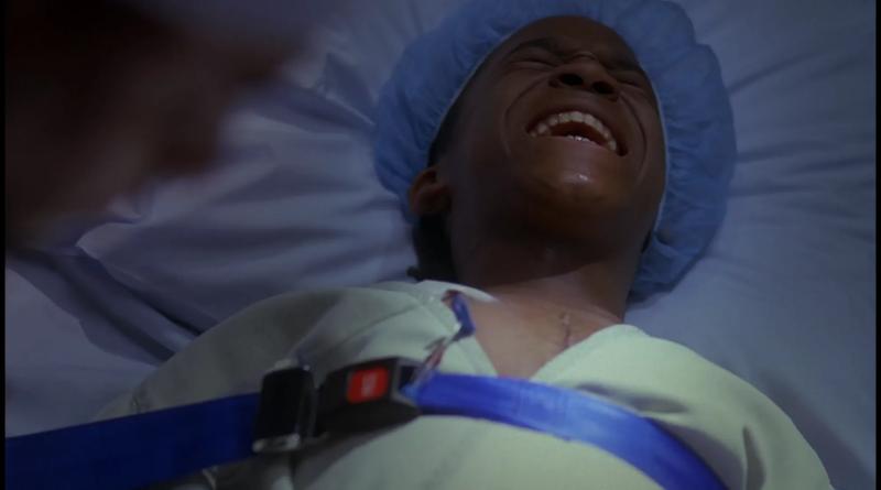 A boy screaming in pain while strapped to a hospital bed