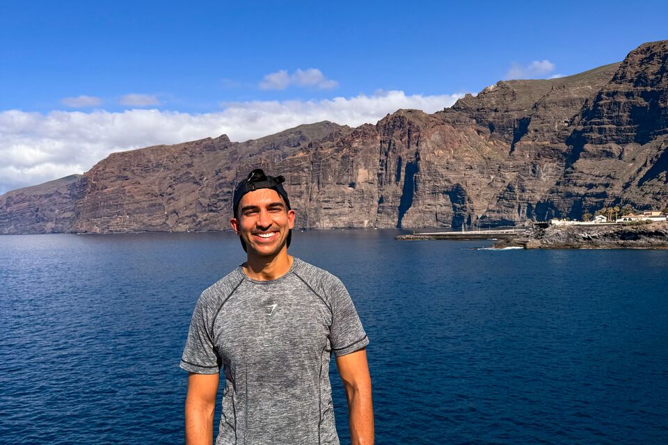 Kash, a man in a grey tshirt and black shorts standing in front of a lake
