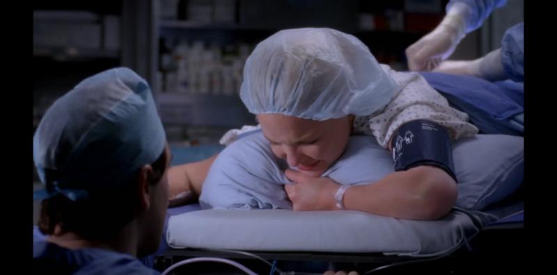 A patient gripping a pillow in pain as a doctor performs a bone marrow aspiration without anaesthetic