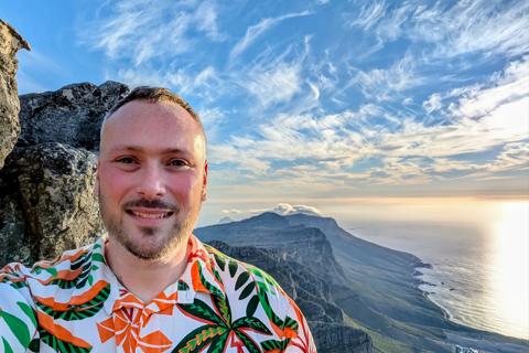 Liam taking a selfie in a colourful shirt with the sunset in the background