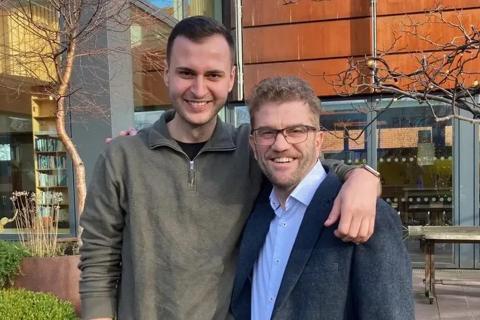 Nick and Marius smiling at the camera arm in arm