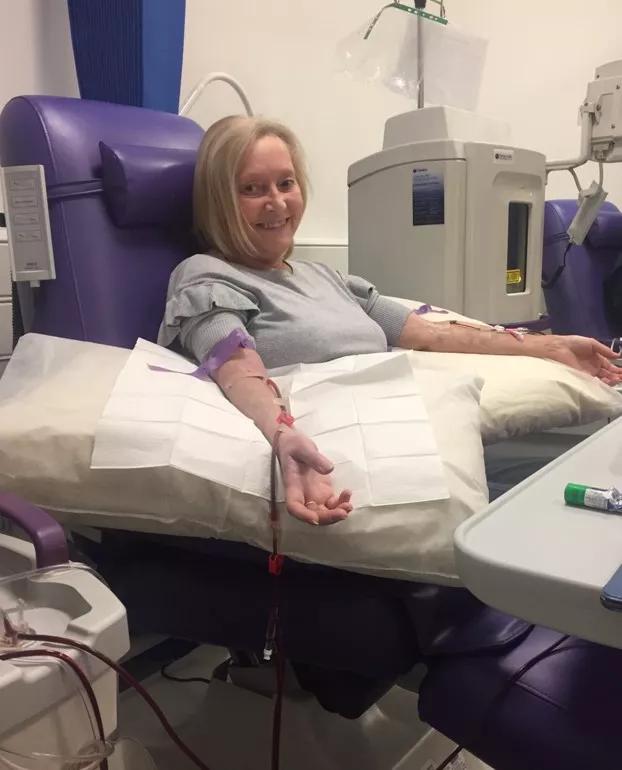 a woman in a hospital bed with an IV in her arm for treatment, she is smiling 