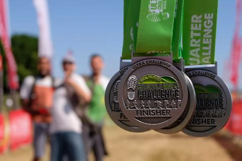 Photo of a medal which says Cotswold Way Challenge on it and has a green ribbon