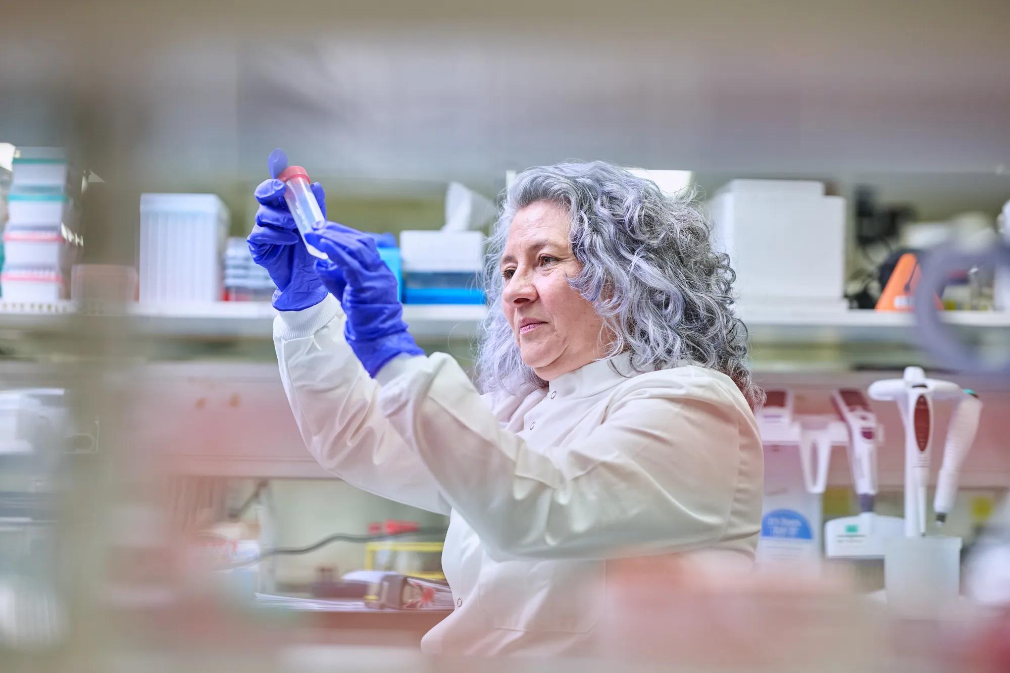 Researcher in a lab setting examining a DNA LoBind tube
