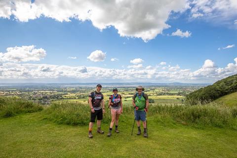 A photo of 3 people stood in the Kent Downs national landscape with lots of greenery behind them and bright blue skies
