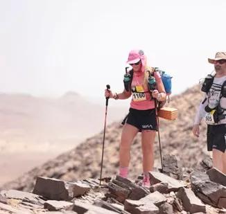 a women hiking across rocks with poles