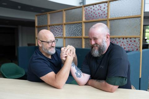 Two white middle-aged men arm wrestling laughing and smiling