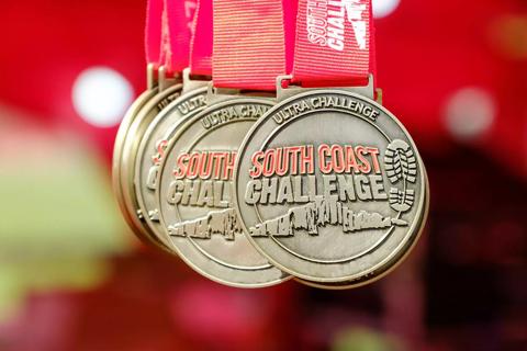 Photo of a medal which says South Coast Challenge and has a red ribbon
