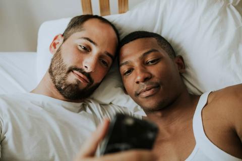 Male couple looking at a phone in bed