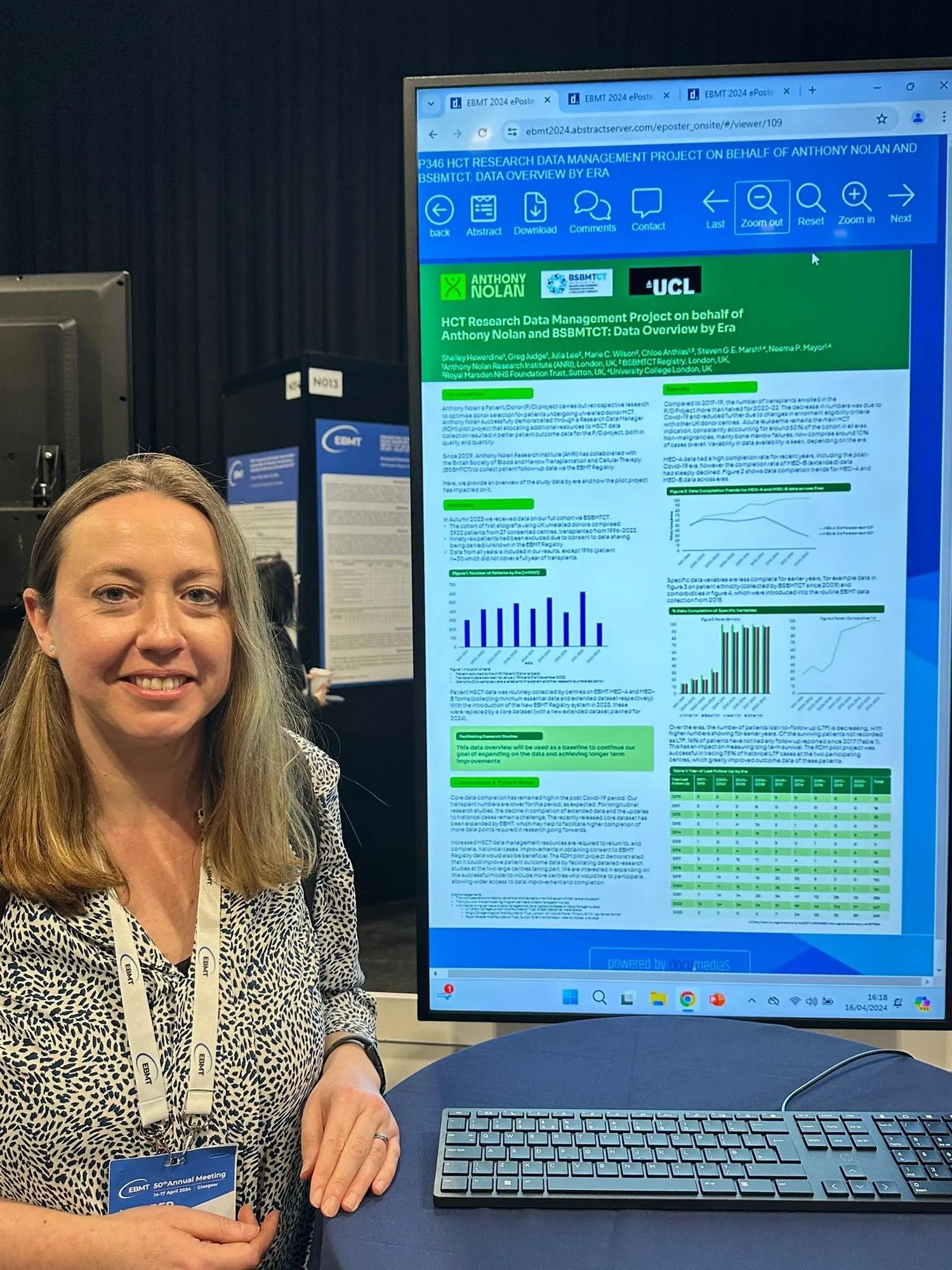 A smiling scientist presents their poster at a scientific conference