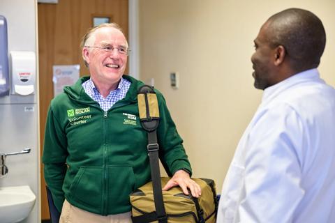Volunteer courier holds courier bag while talking to scientist.