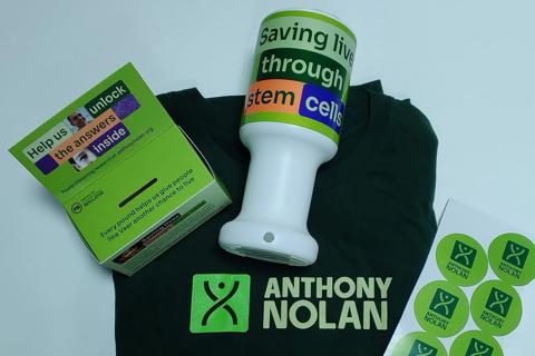 A flat lay image of the Anthony Nolan branded fundraising pack that includes a tshirt, collection box and tin and stickers