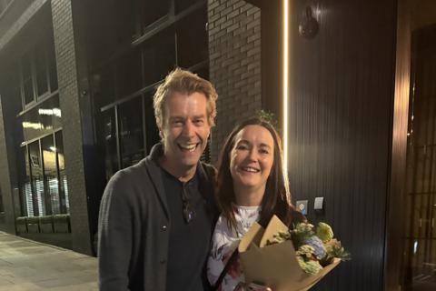 Ian and Rachel hugging in a dark street, Rachel is holding a bunch of flowers
