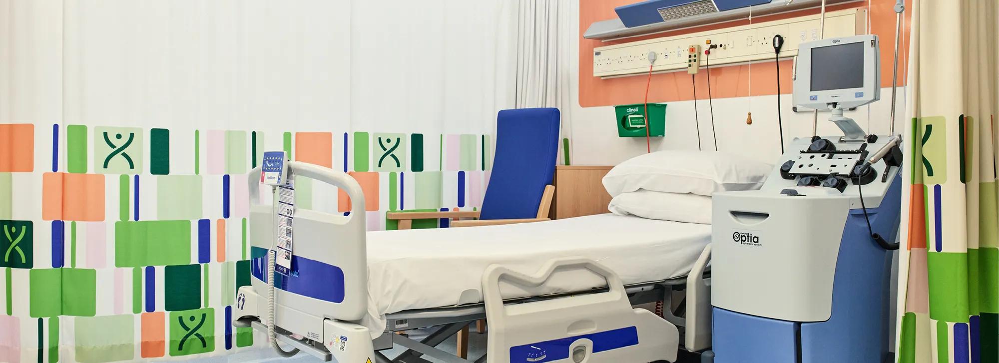 Banner image of an empty donor bed within Anthony Nolan's Cell Collection Centre. Along with colourful branded curtains.