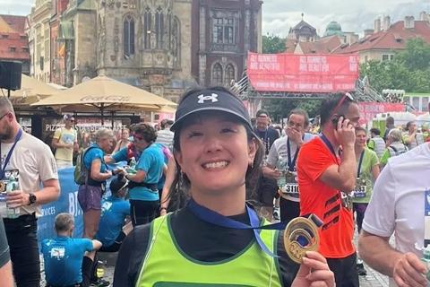 Photo of a woman smiling with her medal and anthony nolan vest after running the prague marathon