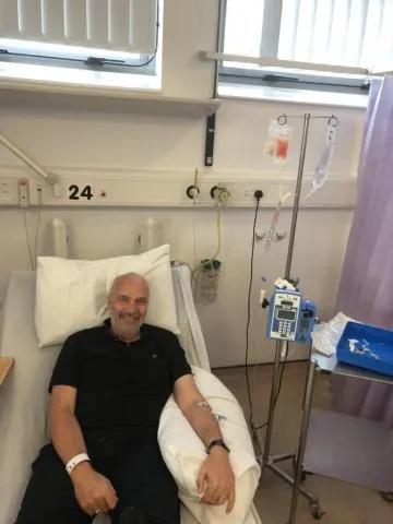 Mark in a hospital chair smiling at the camera