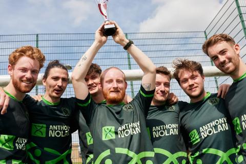 Football team in Anthony Nolan branded kit lifting trophy
