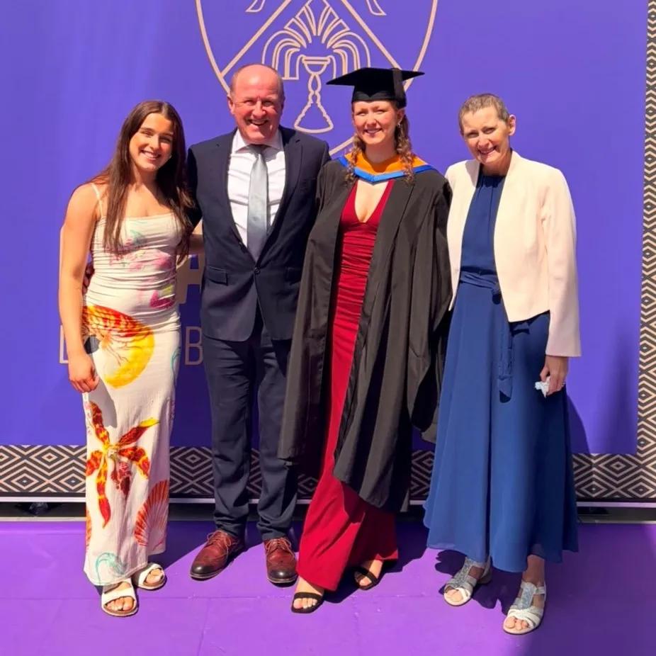 Ruth on right stood next to daughter in graduation gown and family