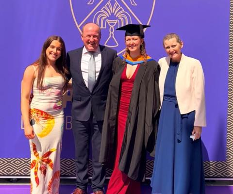 Ruth on right stood next to daughter in graduation gown and family