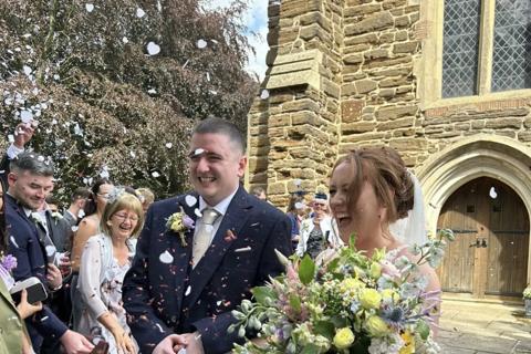 a bride and groom outside a church smiling as confetti is thrown on them