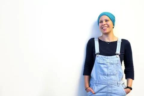 Emma leaning against a white wall smiling
