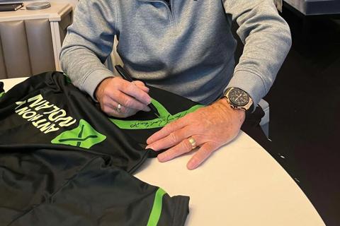 Harry Redknapp signing a green Anthony Nolan football shirt