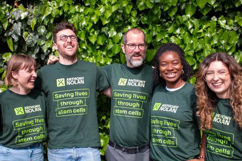 A group of men and women in Anthony Nolan tshirts with their arms around each other smiling and laughing