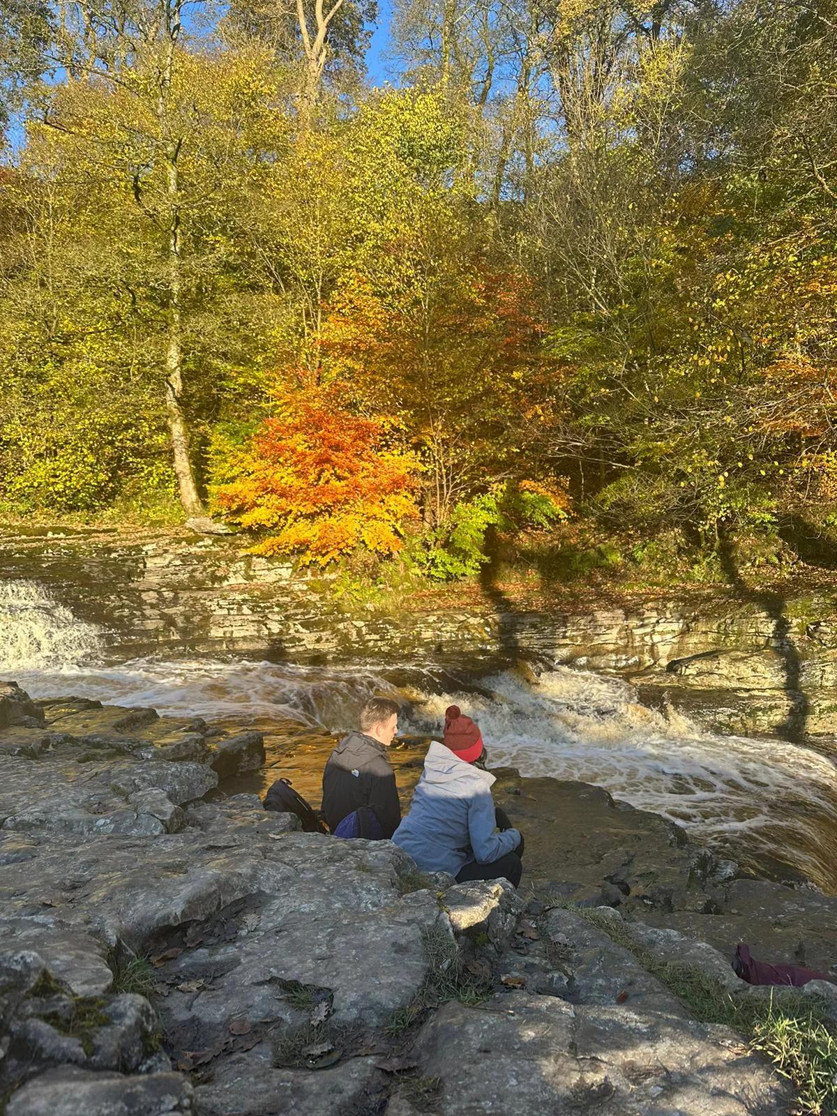 Michaela resting by a river on a hike