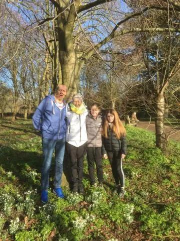 Mary and her family standing in some woodland in the sunshine smiling at the camera
