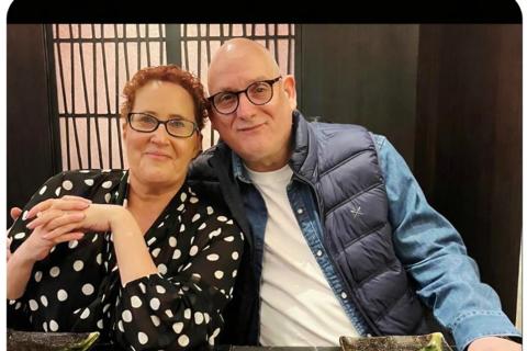 a photo of Emma and her husband, they are sitting at a table and he has his arm around her