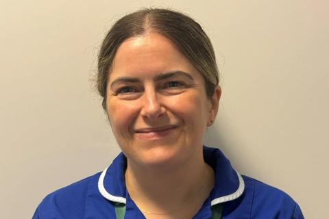 Karen in her blue nurse scrubs smiling for the camera 