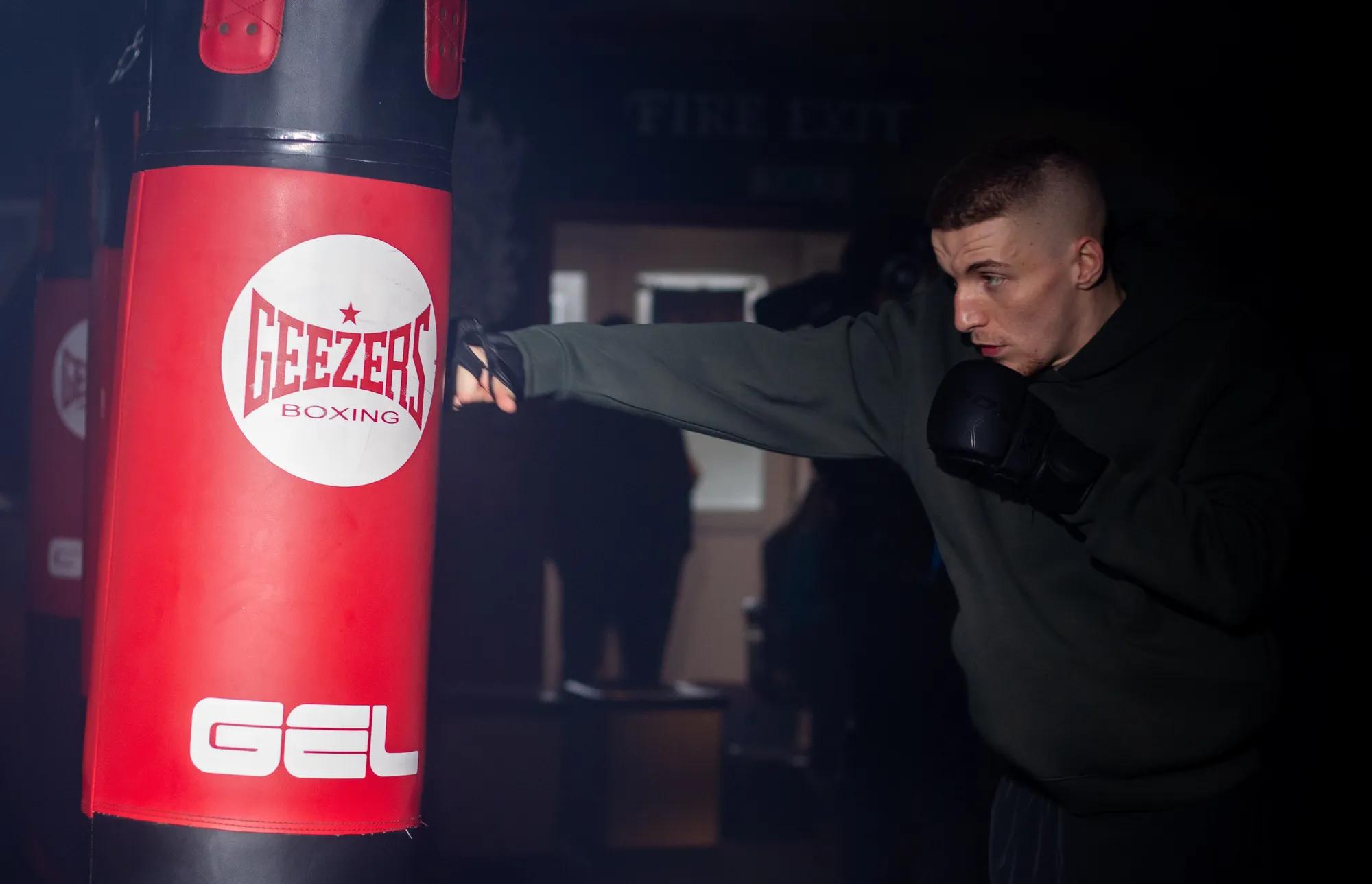 A young man named Charlier hitting a heavy punchbag in a Gym