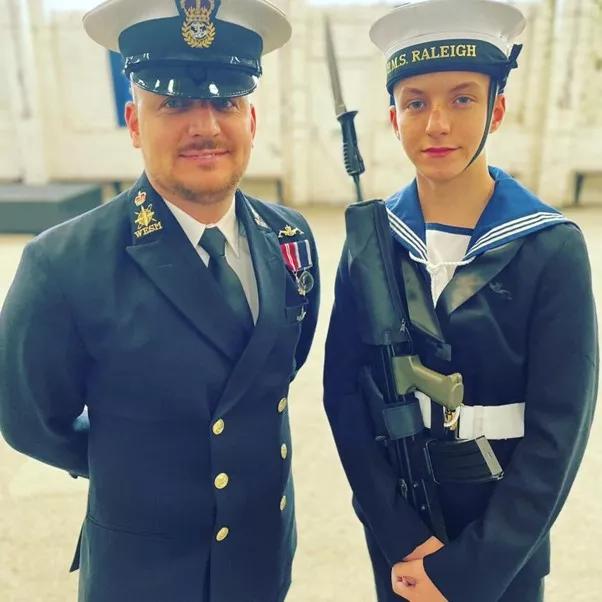 Charlie, a young man standing with his dad in their Royal Navy uniforms