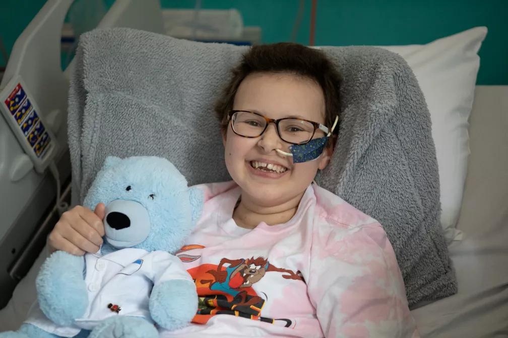 13-year-old Alyssa smiling while lying in a hospital bed.