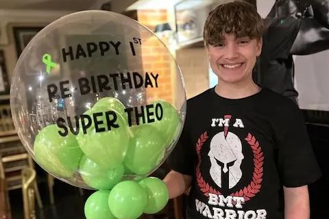 a teenage boy holding a balloon saying happy 1st re-birthday super theo