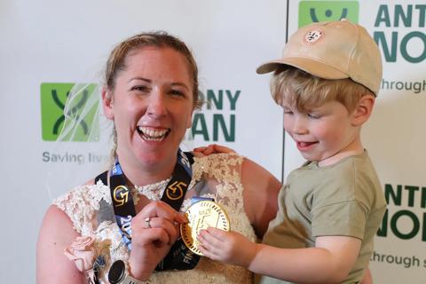 Laura and her son, with her London Marathon medal, wearing a wedding dress after running in memory of her husband