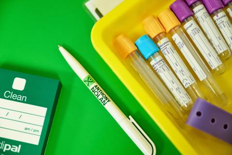 Blood sample vials on a yellow tray next to an Anthony Nolan branded pen.