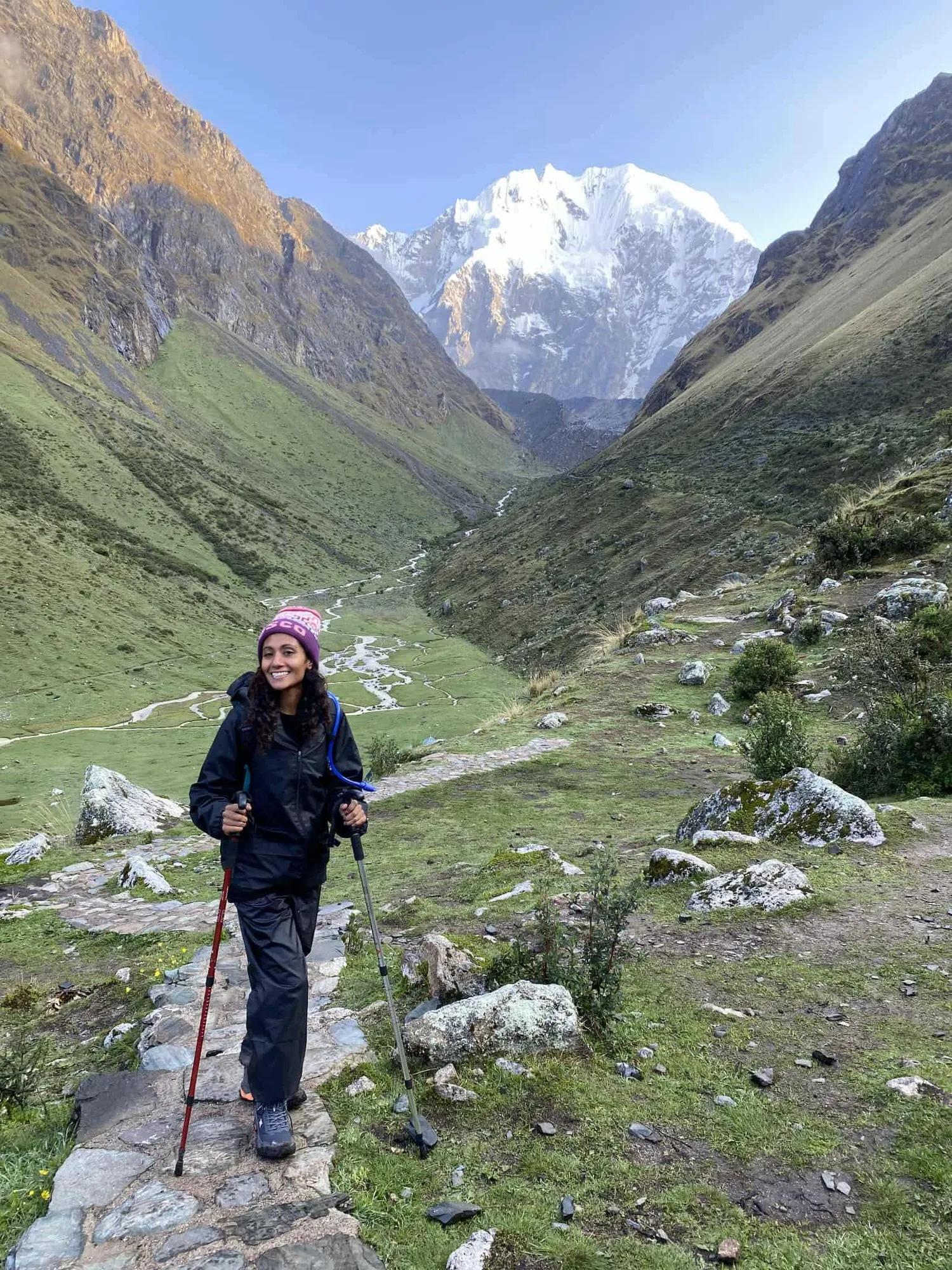 Anie standing amongst mountains with hiking sticks