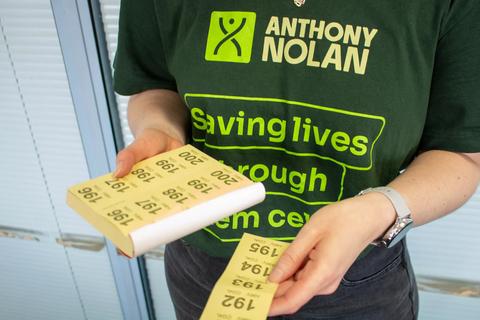 Close up of a person wearing an Anthony Nolan tshirt a book of raffle tickets in their hands