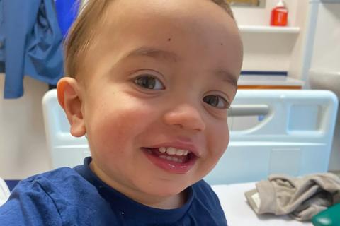 A little boy, Elijah Jones, smiling while sat in a hospital bed