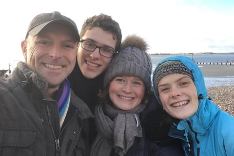 Joanna with her husband and two children all smiling at the camera on the beach in winter