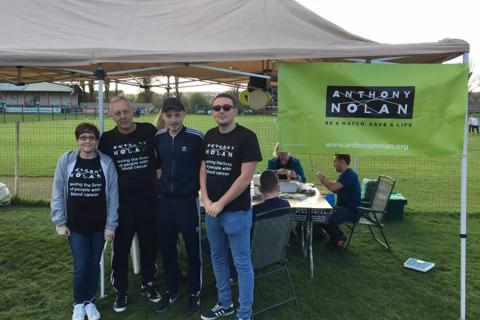 A man, woman and two young men standing in front of an Anthony Nolan banner