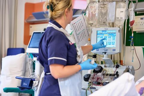 Nurse adjusts apheresis machine.