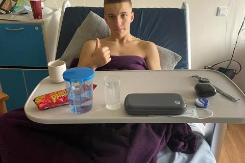 Charlie in a hospital bed giving a thumbs up