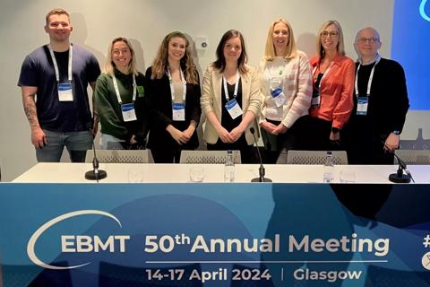 7 of the patient services team at the EBMT event. They are wearing a mix of formal and smart casual cothes with a lanyard around their necks.