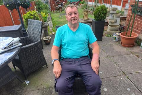 a man sitting in a chair in a garden facing the camera