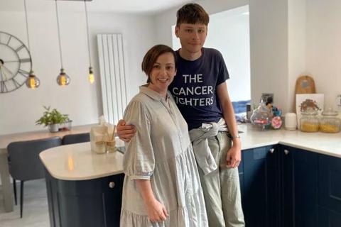 A young man and a woman with their arms around each other, standing in a kitchen