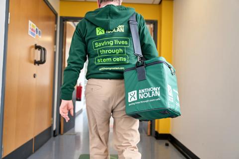 Volunteer courier walks through hospital corridor with courier bag.