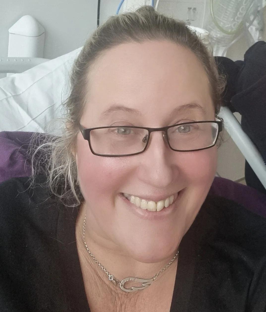 a headshot of Emma smiling, she is wearing glasses and has tied back blond hair