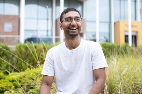 Portrait of a young South Asian man sat outside happy and smiling